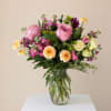 Mixed pink and cream flowers arranged in a clear glass vase