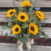Bouquet of yellow sunflowers in a glass vase with a burlap bow