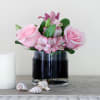 Pink roses and lilies arranged in a clear glass vase