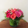 Pink and coral roses arranged in a green glass vase
