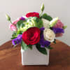 Bouquet of red, white, pink, and purple flowers in a white square vase