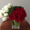 Red roses and white tulips in a clear glass vase