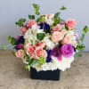 Mixed pink, white, and purple flower arrangement in a black box