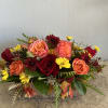 Arrangement of red and peach roses with yellow daisies in a low container