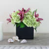 Pink lilies and pale green hydrangeas in a black square vase