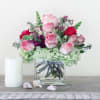 Pink and red roses in a clear glass vase with pale green hydrangeas