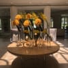 Yellow rose arrangements in tall glass vases on a round table with candles