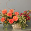 Orange dahlias and red flowers in a metallic vase