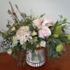 Pink roses and pale blooms arranged in a ceramic vase