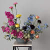 Mixed bouquet in a gray vase with pink, yellow, blue, and peach flowers
