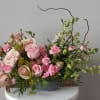 Pink and peach roses with small pink blooms in a low gray bowl