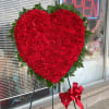 Heart-shaped red carnation standing spray with a ribbon on an easel