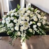 White floral casket spray with roses, lilies, and chrysanthemums