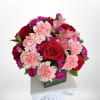 A dense, rounded cluster of red roses and pale pink carnations gives