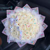 Bouquet of white roses wrapped in pink paper with a white ribbon