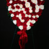 Heart-shaped arrangement of red and white roses with a red ribbon