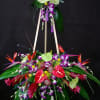Tall tropical floral standing arrangement on an easel with purple, red, and white blooms
