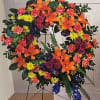 Large floral wreath with orange lilies, pink roses, and yellow and coral blooms