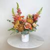 Mixed bouquet in a white vase with orange, pink, and gold blooms