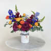 Colorful mixed bouquet in a white vase with a striped ribbon
