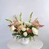Pink and white mixed bouquet in a white vase with a striped ribbon