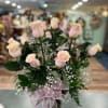 Pink roses arranged in a glass vase with a pink ribbon bow