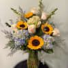 Bouquet of sunflowers, pale roses, and hydrangeas in a glass vase