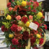 Large bouquet of red, yellow, and orange flowers with a yellow ribbon