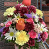 Mixed bouquet in a pink metal bucket with roses, daisies, and carnations