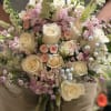 Handheld bouquet of cream roses and pastel pink flowers