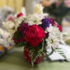 Red carnations and white daisies in a red vase