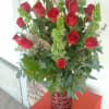 Tall bouquet of red roses with green filler in a decorative vase