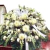Large white funeral spray with lilies and ribbon on a stand