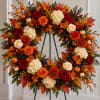 Autumn wreath with roses, hydrangeas, and pumpkins on a stand