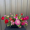 Pink and red mixed flower arrangement in a black container