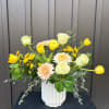 Yellow tulips and pale roses in a white vase with peach chrysanthemums
