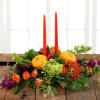 A traditional autumn centerpiece featuring mini pumpkins and tapered candles to create