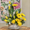 Yellow tulips and gerbera daisies arranged in a glittered vase