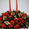Red floral centerpiece with two tall candles and ribbon accents