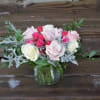 Pink and white roses in a glass vase with silver foliage
