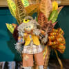 Fall scarecrow decoration in a basket with colorful leaves and ribbon