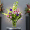 Mixed bouquet in a clear glass vase with pink, yellow, purple, and white flowers