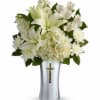 White floral arrangement in a silver vase with a cross emblem