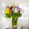Mixed bouquet of roses, lilies, and irises in a glass vase