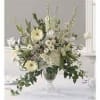 White floral arrangement in a clear vase with tall stems and trailing greenery