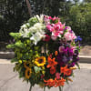 Large standing floral spray with lilies, roses, and sunflowers