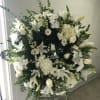 Large white funeral wreath on an easel with lilies and roses