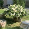 Large white floral arrangement with daisies and roses in an outdoor setting