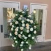 Standing spray of white roses and greenery on an easel
