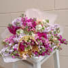 Large bouquet of pink, lavender, and white flowers with a gold handle